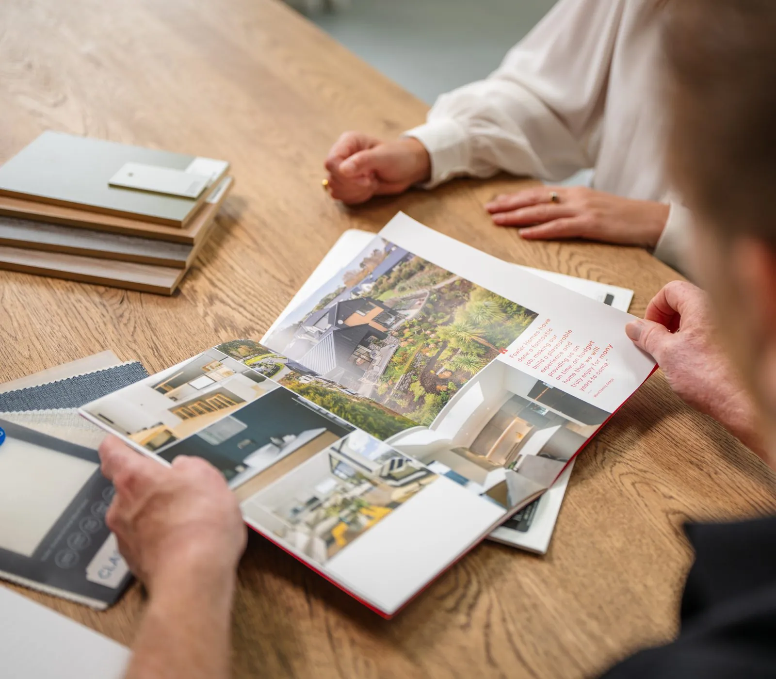 A Fowler Homes booklet open on a table alongside material samples