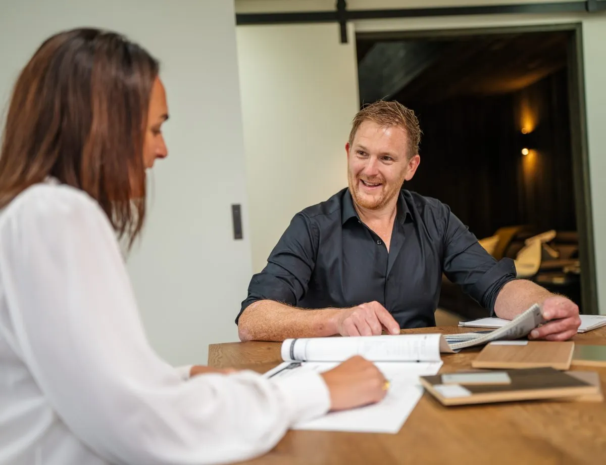 A Fowler Homes builder talking a client through plans and samples at a table
