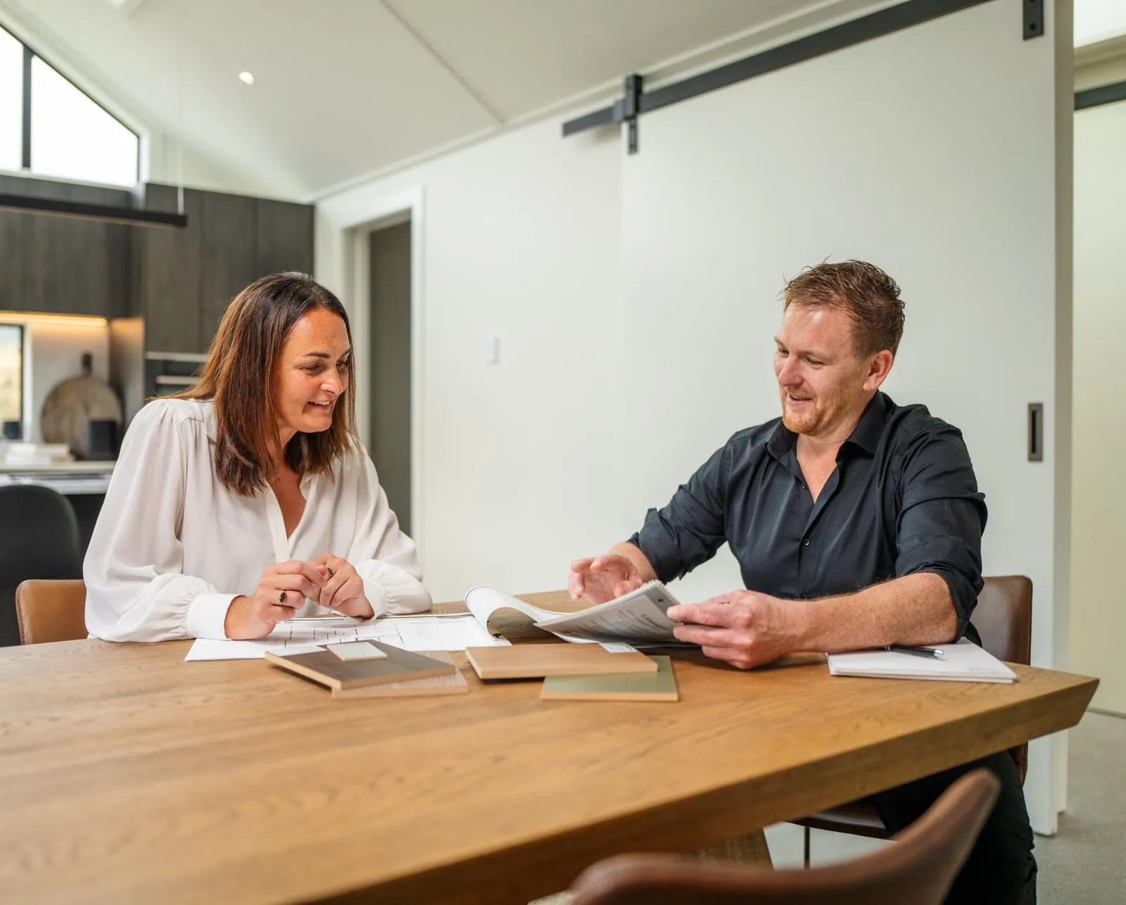 A couple going through Fowler Homes plans and samples at a dining table